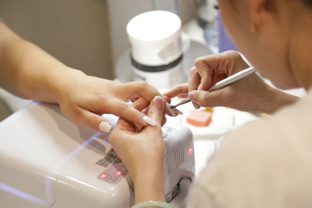 Manicure aplicando alongamento na unha de uma cliente em salao